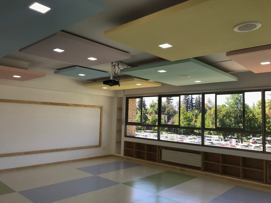Sala con cielos flotantes de colores y ventanales hacia los árboles