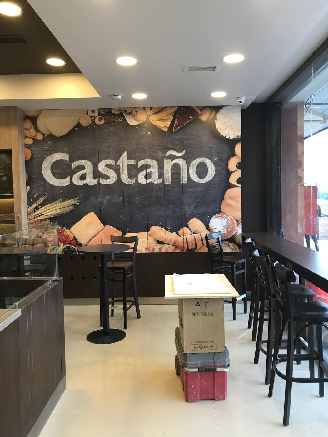 Zona de mesas altas con gráfica de Castaño junto al ventanal