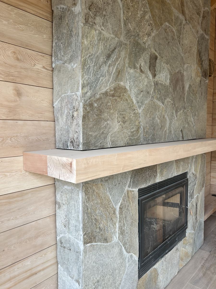 Chimenea de piedra con repisa de madera maciza