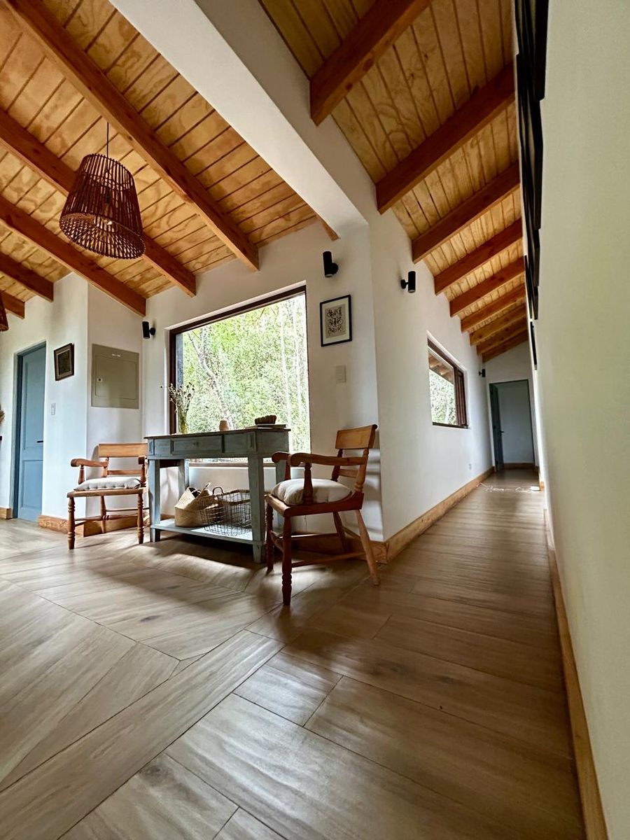 Hall con ventanal hacia el bosque y piso en espiga