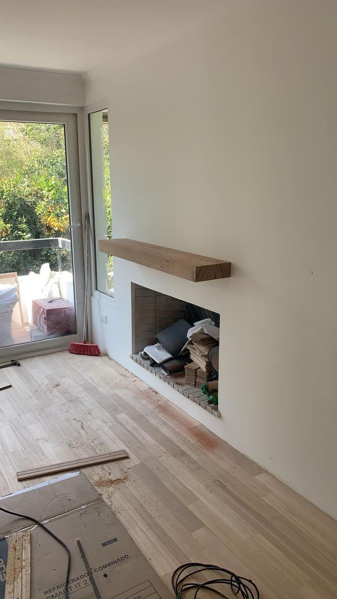 Chimenea con repisa de madera maciza junto al termopanel